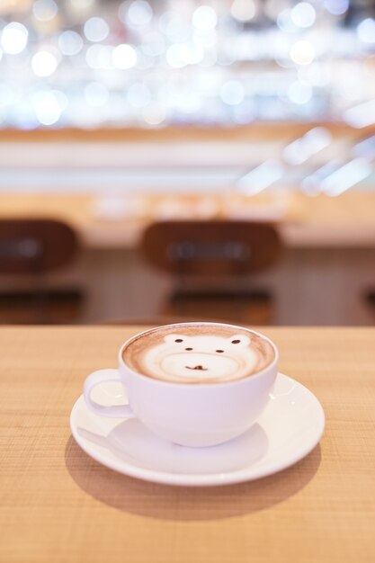 Schattige beer latte warme koffie in witte kop op houten tafel, lees om te serveren.