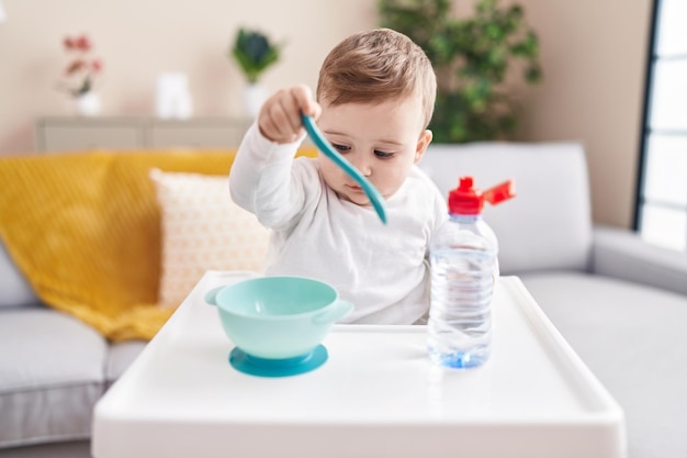 Schattige blanke baby zittend op kinderstoel thuis eten