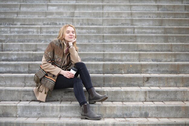 Schattige blonde in de stad koffie drinken op de trap