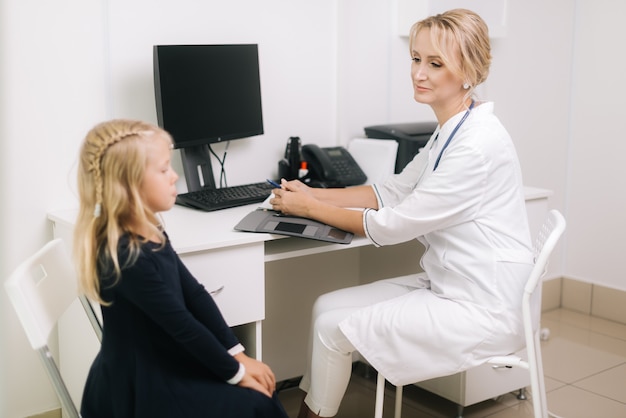 Schattige blonde jongen meisje patiënt zit op stoel praten met vrouw arts