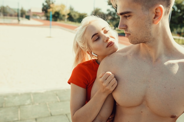 Schattige blonde knuffelt haar atletische vriendje