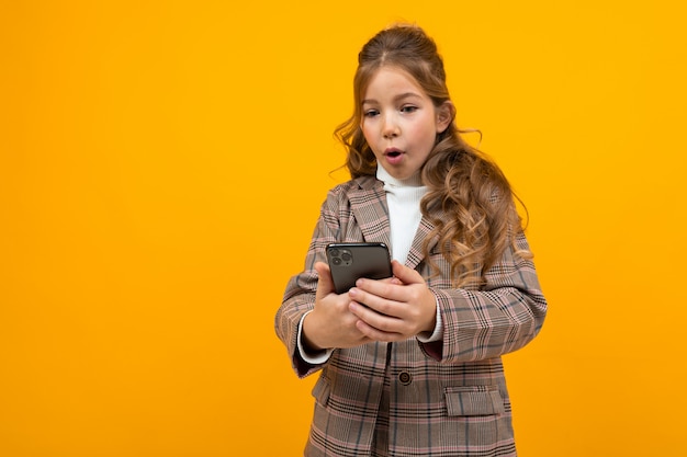 Schattige blonde meisje in een klassieke jas maakt selfie aan de telefoon in de met een geel