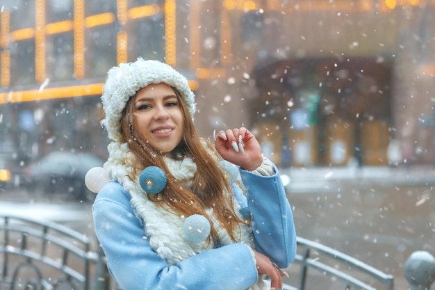 Schattige blonde vrouw die plezier heeft op de kerstmarkt tijdens sneeuwval. Lege ruimte