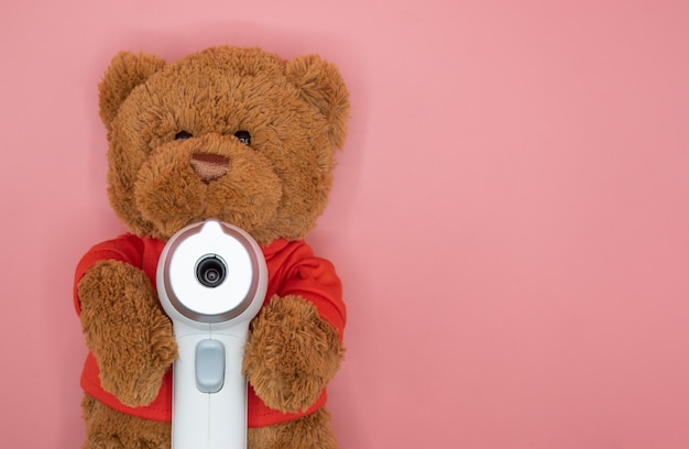 Schattige bruine teddybeer houdt medische infrarood voorhoofdthermometer