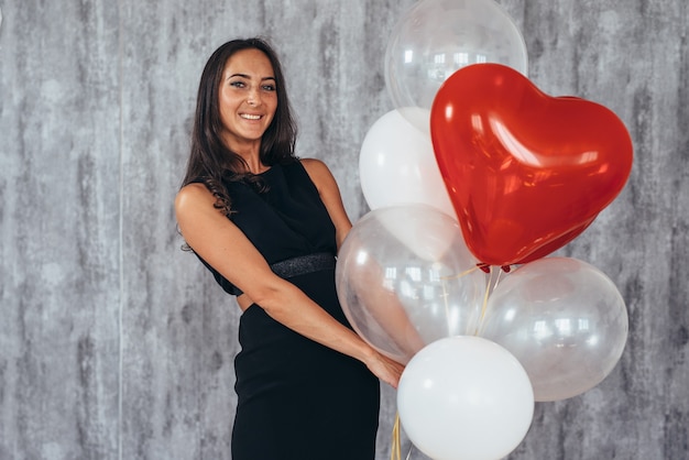 Schattige brunette vrouw glimlachend en spelen met ballonnen.