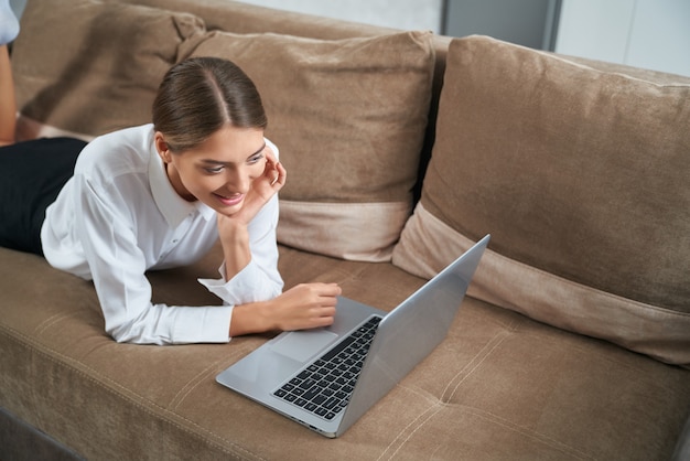 Schattige dame die laptop gebruikt tijdens vrije tijd thuis