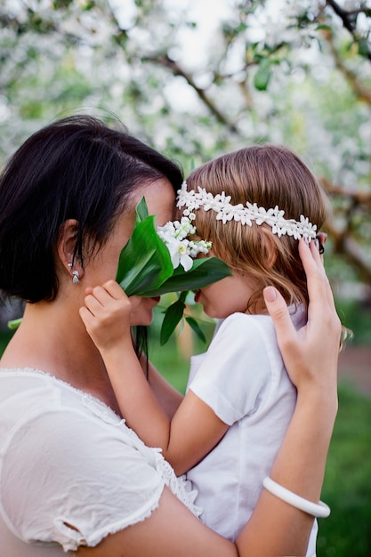 Schattige dochter en moeder knuffelen in bloesem lentetuin