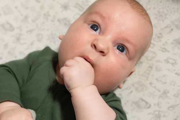 schattige drie maanden oude baby die zijn hand eet Tandjes krijgen