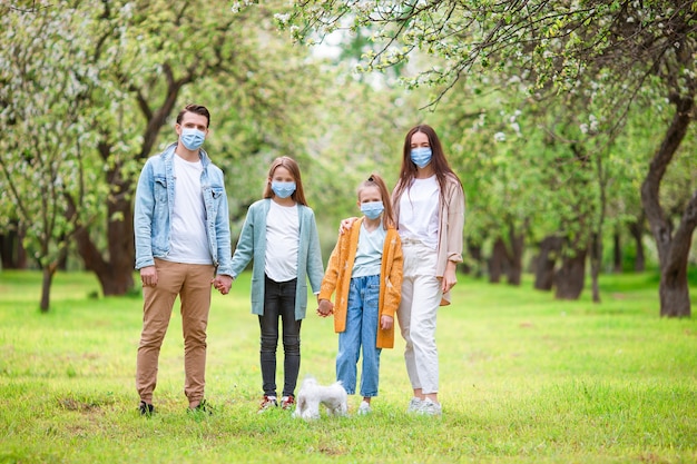 Schattige familie in bloeiende kersentuin in maskers