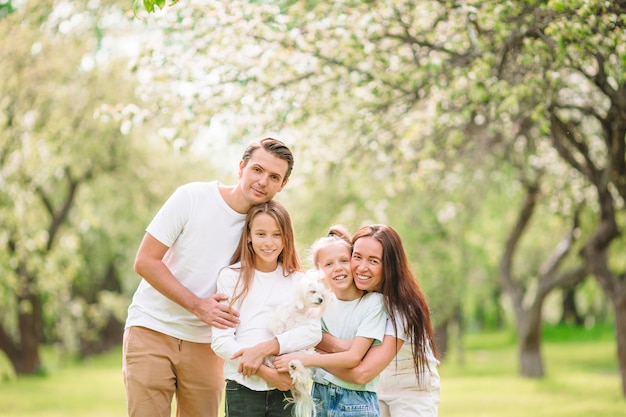 Schattige familie in bloeiende kersentuin op mooie de lentedag