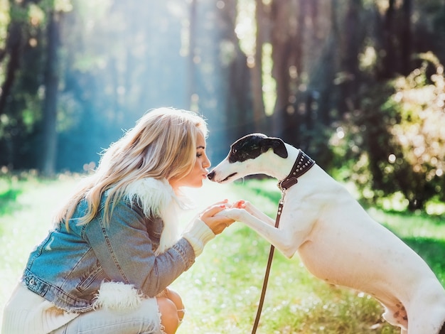 schattige gelukkige blonde vrouw eigenaar met haar witte whippet buiten