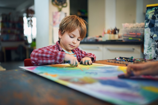 Schattige gelukkige kleine jongen, schattige peuter, schilderen in een zonnige kunststudio.