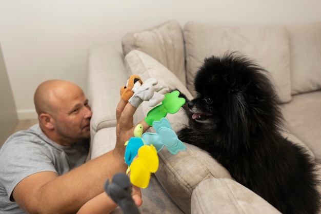 Foto schattige hond die naar zijn baasjes kijkt terwijl hij met poppen speelt