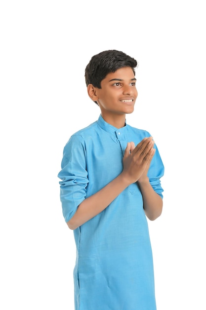 Schattige Indiase kleine jongen bidden en geven namaste of welkome uitdrukking op witte achtergrond