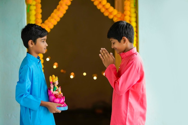 Schattige Indiase kleine jongen godin laxmi sclupture in de hand houden en diwali festival vieren.