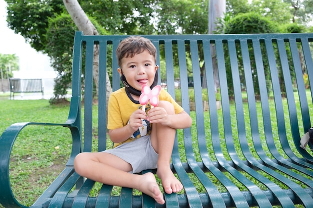 Schattige jonge jongen zittend op een bankje in het park eten van ijs