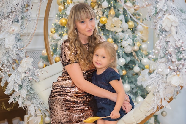 schattige jonge vrouw met haar dochter in de buurt van de kerstboom met kerstmis