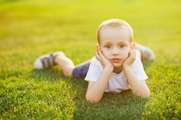 Foto schattige jongen jongen liggend op helder groen gras over zonlicht