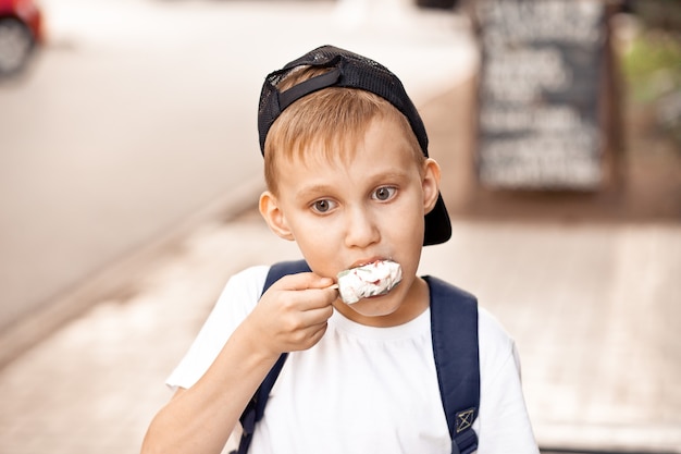 Schattige jongen jongenskind eten van ijs buiten in een park.