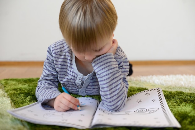 Schattige jongen leest het boek thuis op de vloer