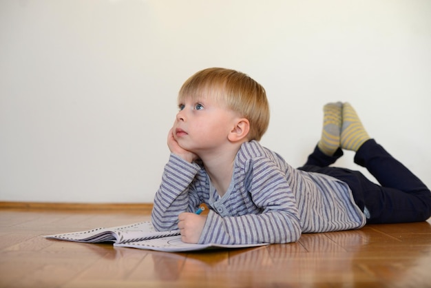 schattige jongen leest het boek thuis op de vloer