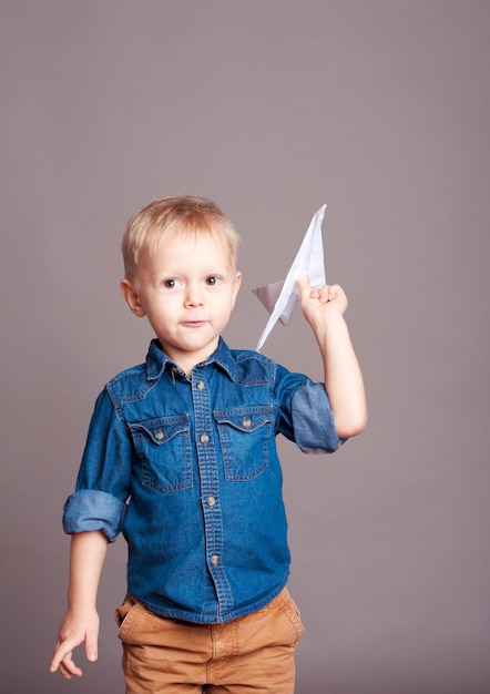 Schattige jongen speelt met origami papieren vliegtuigje