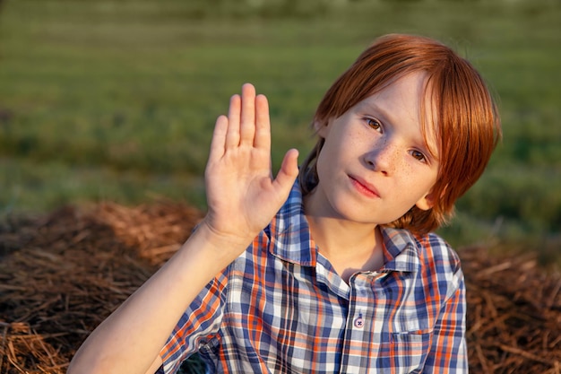 Schattige jongen steekt zijn handpalm omhoog in de natuur, een oproep om de oorlog te stoppen, milieuvervuiling te stoppen