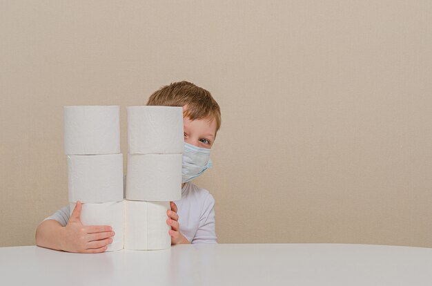 Schattige jongen van vier in een beschermend medisch masker speelt met wc-papier