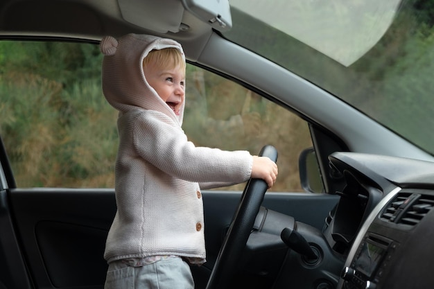 Schattige kaukasische peuter die in de auto rijdt Schattig kind dat lacht achter het stuur