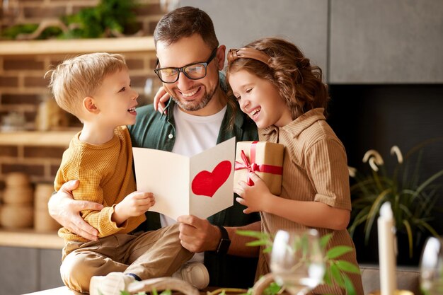 Schattige kinderen feliciteren gelukkige papa met Vaderdag en geven hem een handgemaakte ansichtkaart