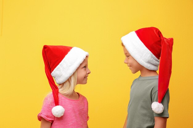 Schattige kinderen in kerstmutsen op gekleurde achtergrond