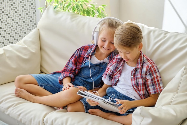 Schattige kinderen met koptelefoon genieten van tablet thuis