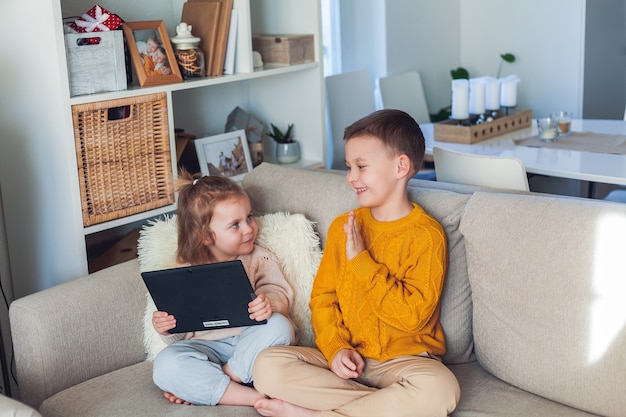 Schattige kinderen praten via een videogesprek met een tablet. Quarantaine. Een familie. Huis. Knus.