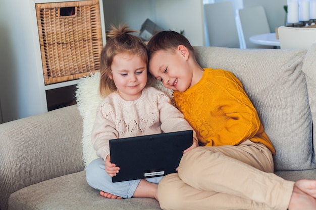 Schattige kinderen praten via een videogesprek met een tablet. Quarantaine. Een familie. Huis. Knus.