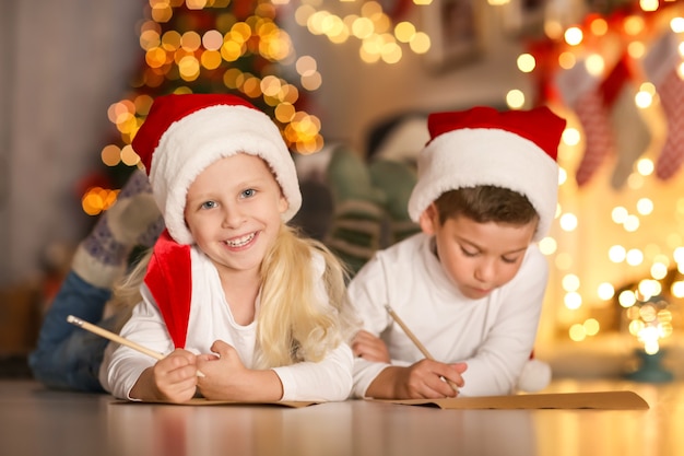 Schattige kinderen schrijven brief aan de kerstman in de kamer ingericht voor kerstmis