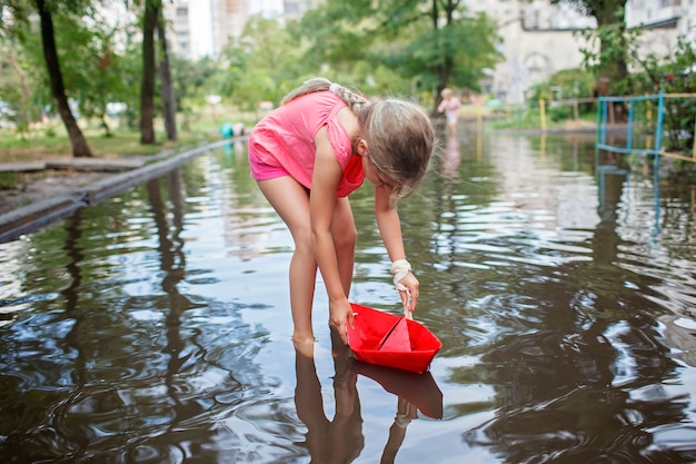 Schattige kinderen spelen met papieren bootje in de plassen na warme zomerregen gelukkige jeugd