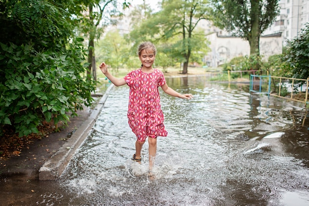 Schattige kinderen springen en zwemmen in de plassen na warme zomerregen gelukkige jeugd