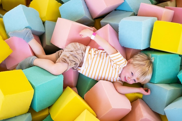 Schattige kinderjongen speelt met zachte blokjes in het droge zwembad in het speelcentrum