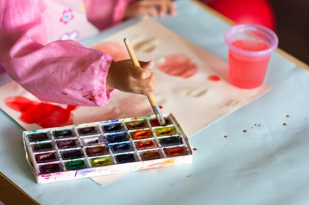 Schattige kinderverf met penseel en kleurrijke verf op papier