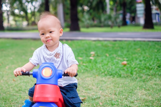 Schattige kleine Aziatische 1-jarige peuter baby boy kind rijdt op zijn driewieler in zomer park