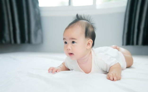 Schattige kleine Aziatische baby op bed met zachte deken binnenshuis