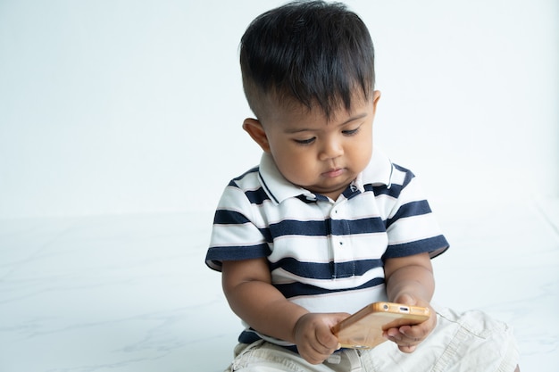 Schattige kleine aziatische babyjongen spelen slimme telefoon