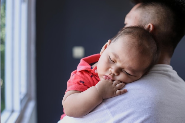 Schattige kleine baby die op zijn vaders schouder slaapt Liefdevolle zorg genegenheid en tederheid vaderho