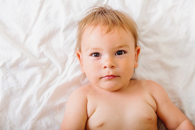 Schattige kleine baby liggend op witte bed en gelukkig lachend, jeugd