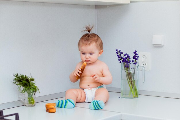 Schattige kleine baby met koekjes zittend op de tafel in de keuken