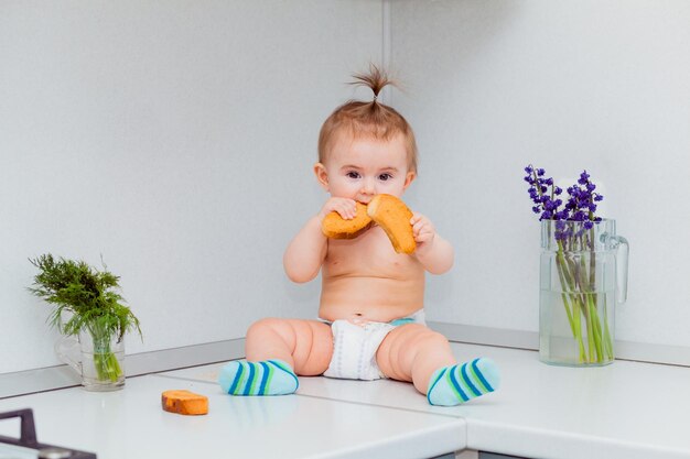 Schattige kleine baby met koekjes zittend op de tafel in de keuken