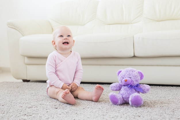 Schattige kleine babymeisje draagt roze kleren zittend op een tapijt