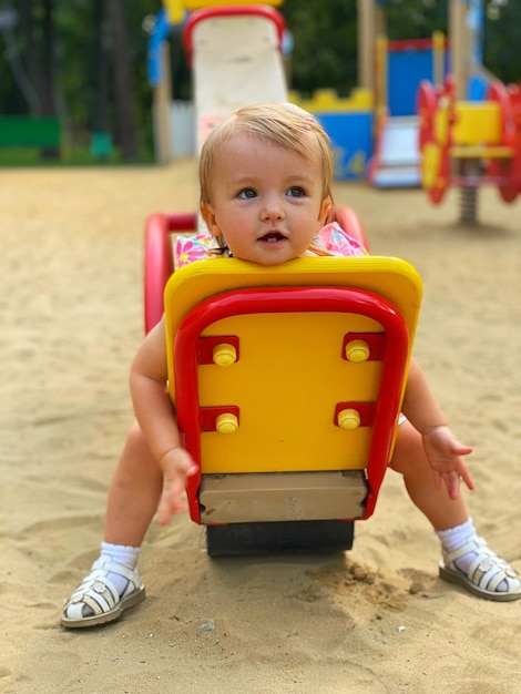 Schattige kleine babymeisje zit op een schommel in de speeltuin