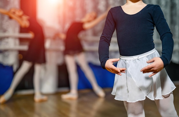 Schattige kleine ballerina in dansstudio poseren en trainen met balletteam op de achtergrond selectieve aandacht close-up