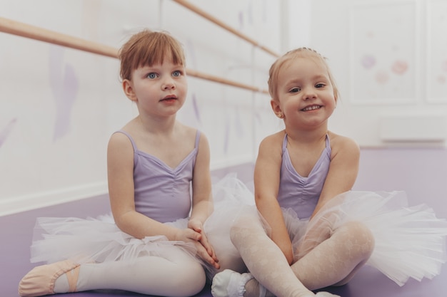 Schattige kleine ballerina's die na het uitoefenen op dansschool rusten